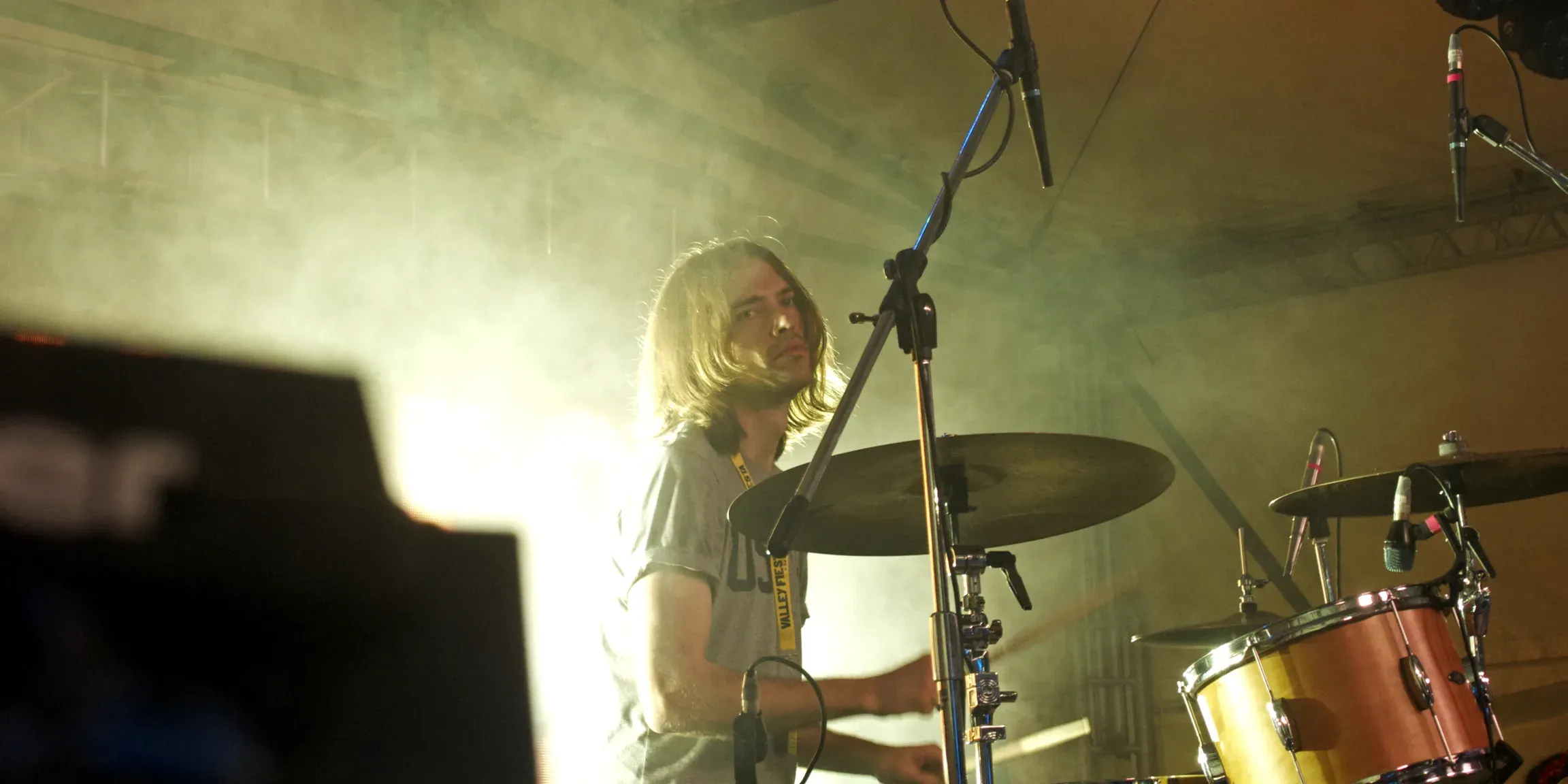 Luke Davison playing a C&C kit live, lit through stage haze